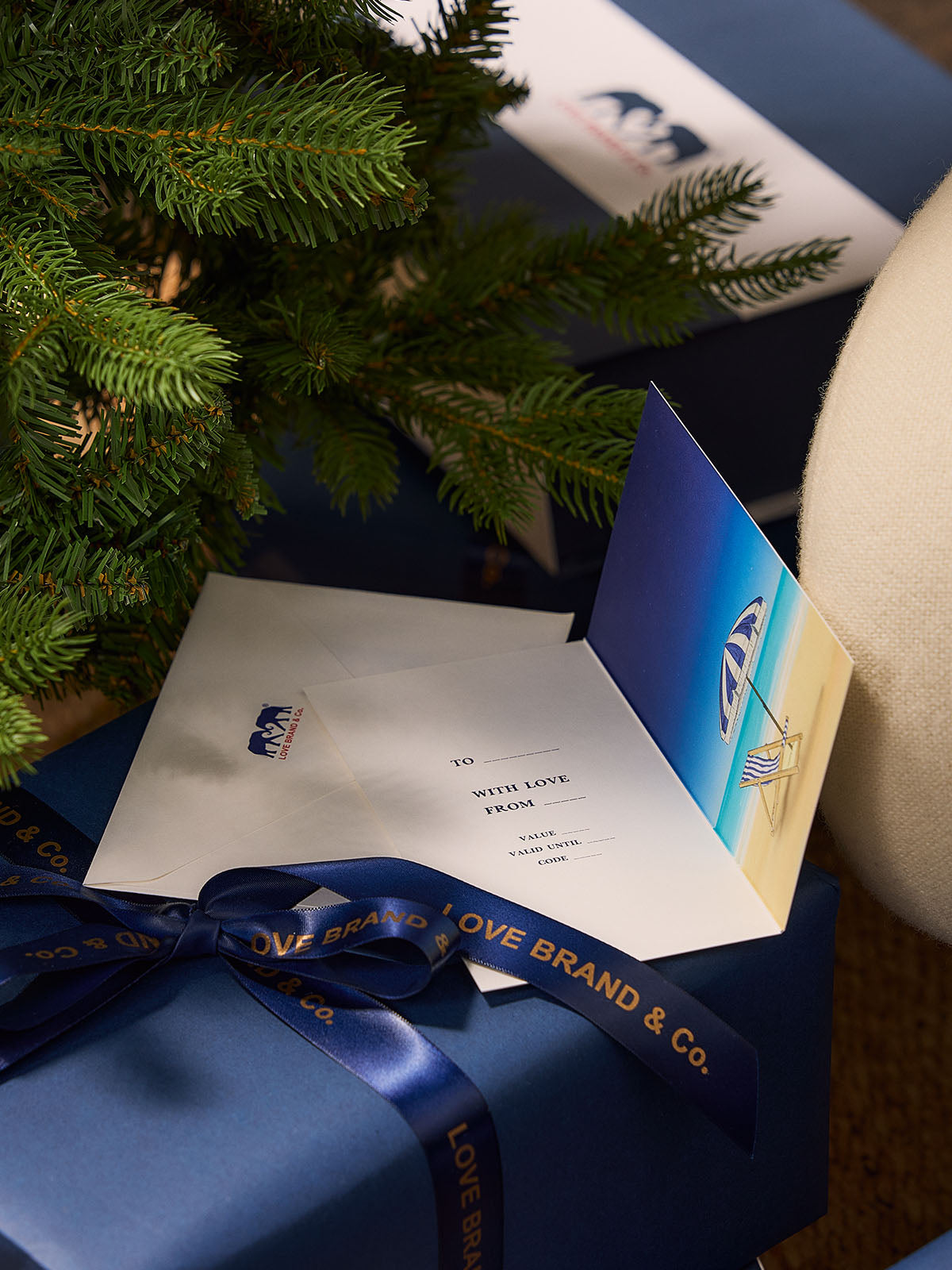 Blue gift box with a card and bow, under a Christmas tree