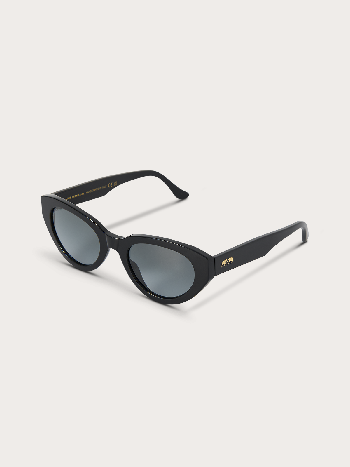 Black cat-eye sunglasses with gold accents on a light gray background