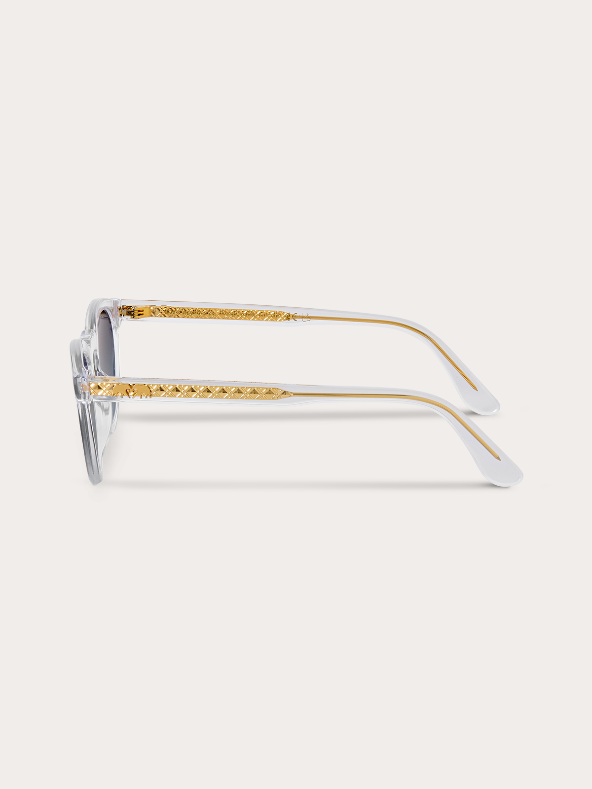Side view of clear sunglasses with gold accents on a white background