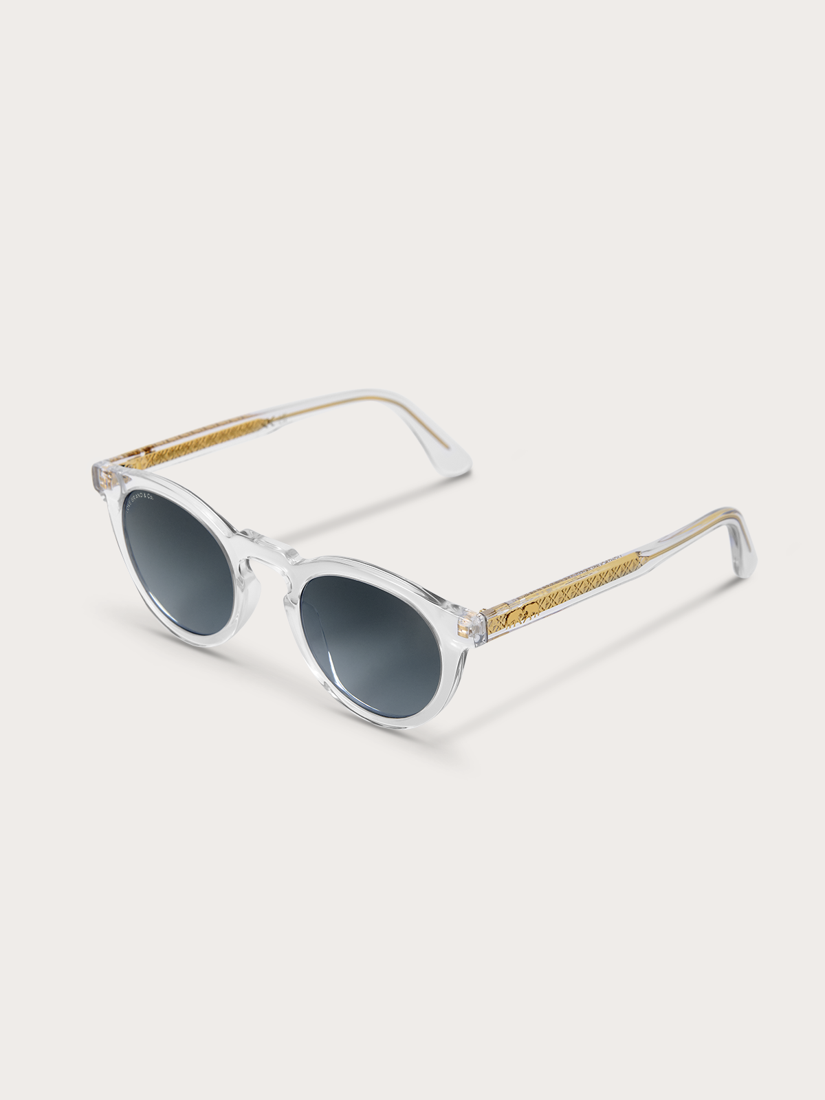 Front down view of clear sunglasses with gold frames on a light background