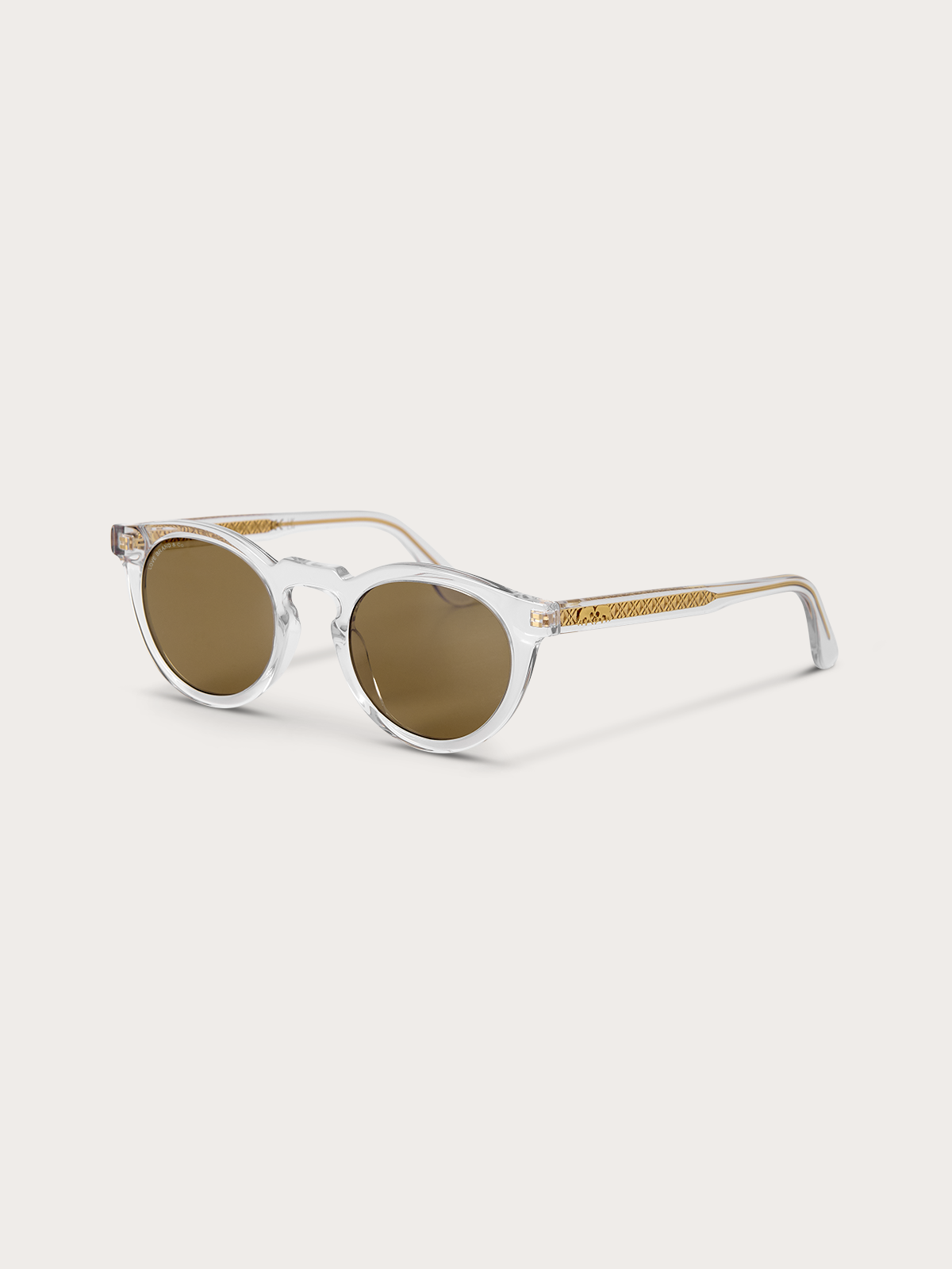 Sideview of clear frame sunglasses with brown lenses on a light grey background