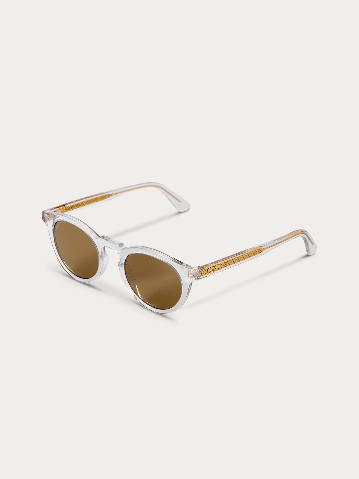 Top down view of clear sunglasses with gold accents and brown lenses on a white background