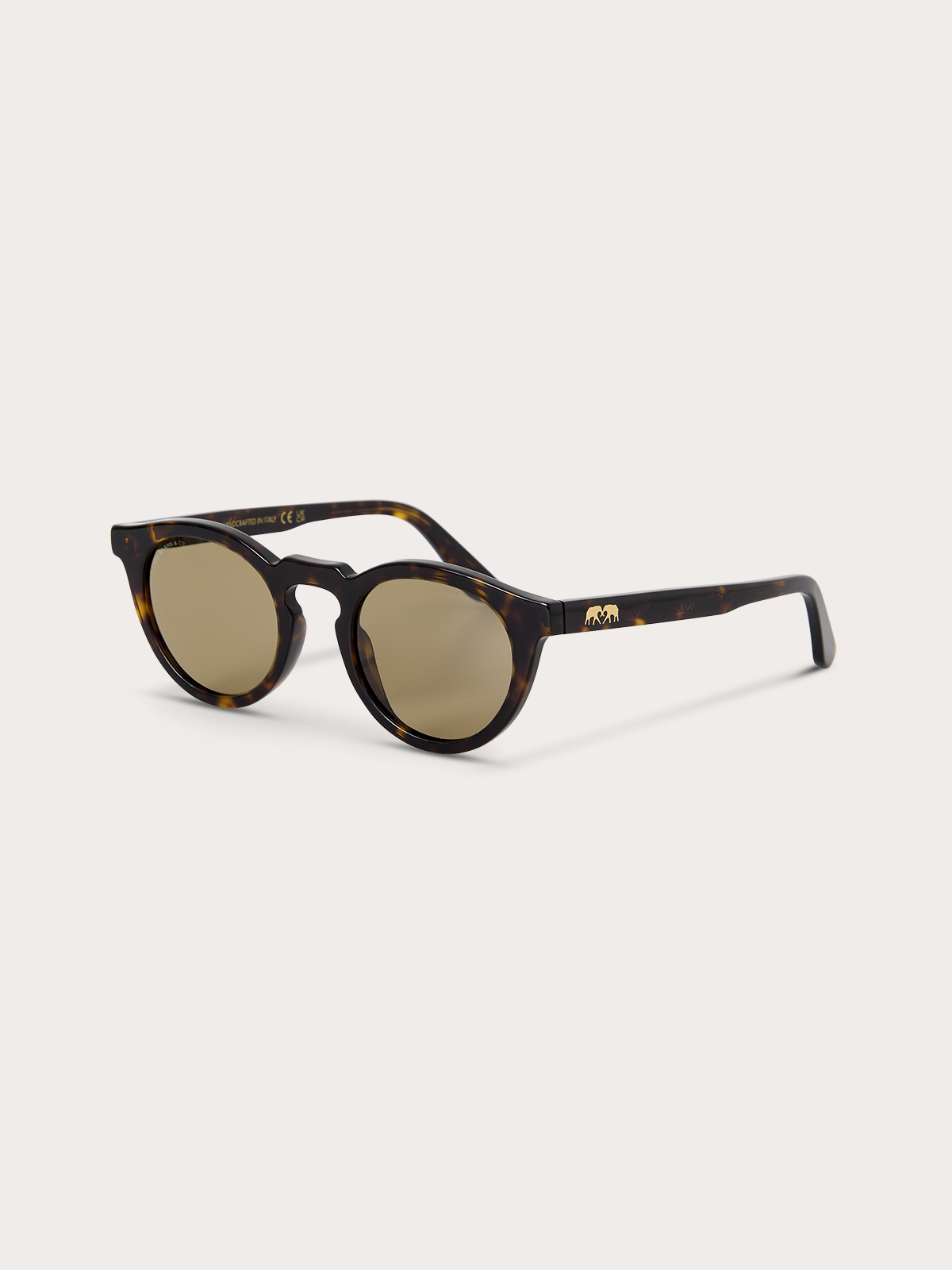 Sideview of round sunglasses with tortoiseshell frame and gold accents on a white background