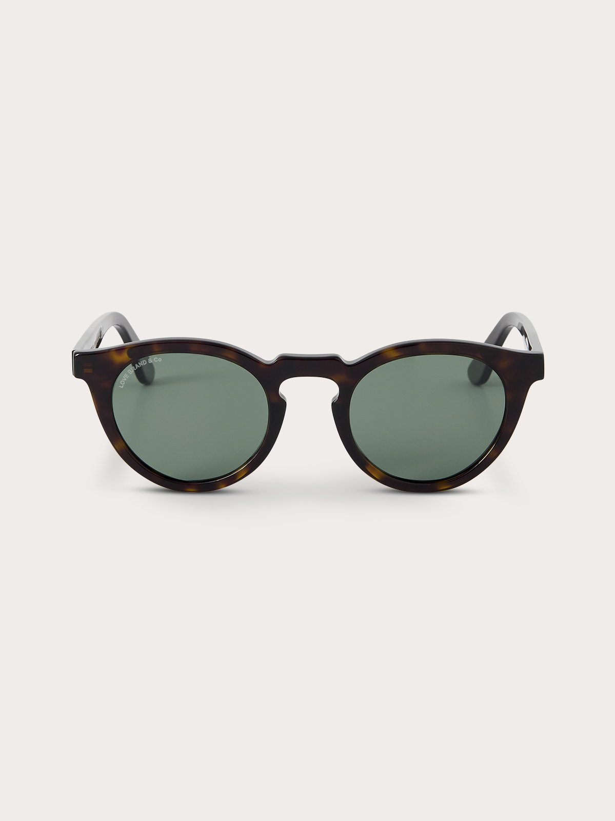 Sunglasses with tortoiseshell frame and green lenses on a white background