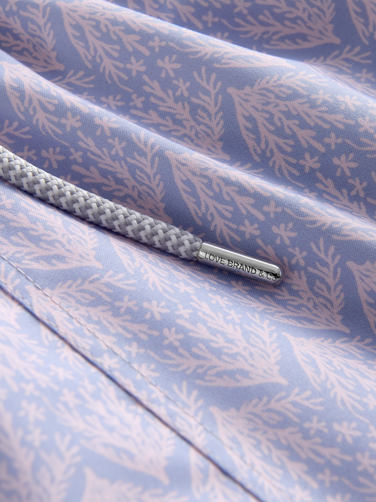 Close-up of swim shorts fabric with a subtle pattern and a brand label.