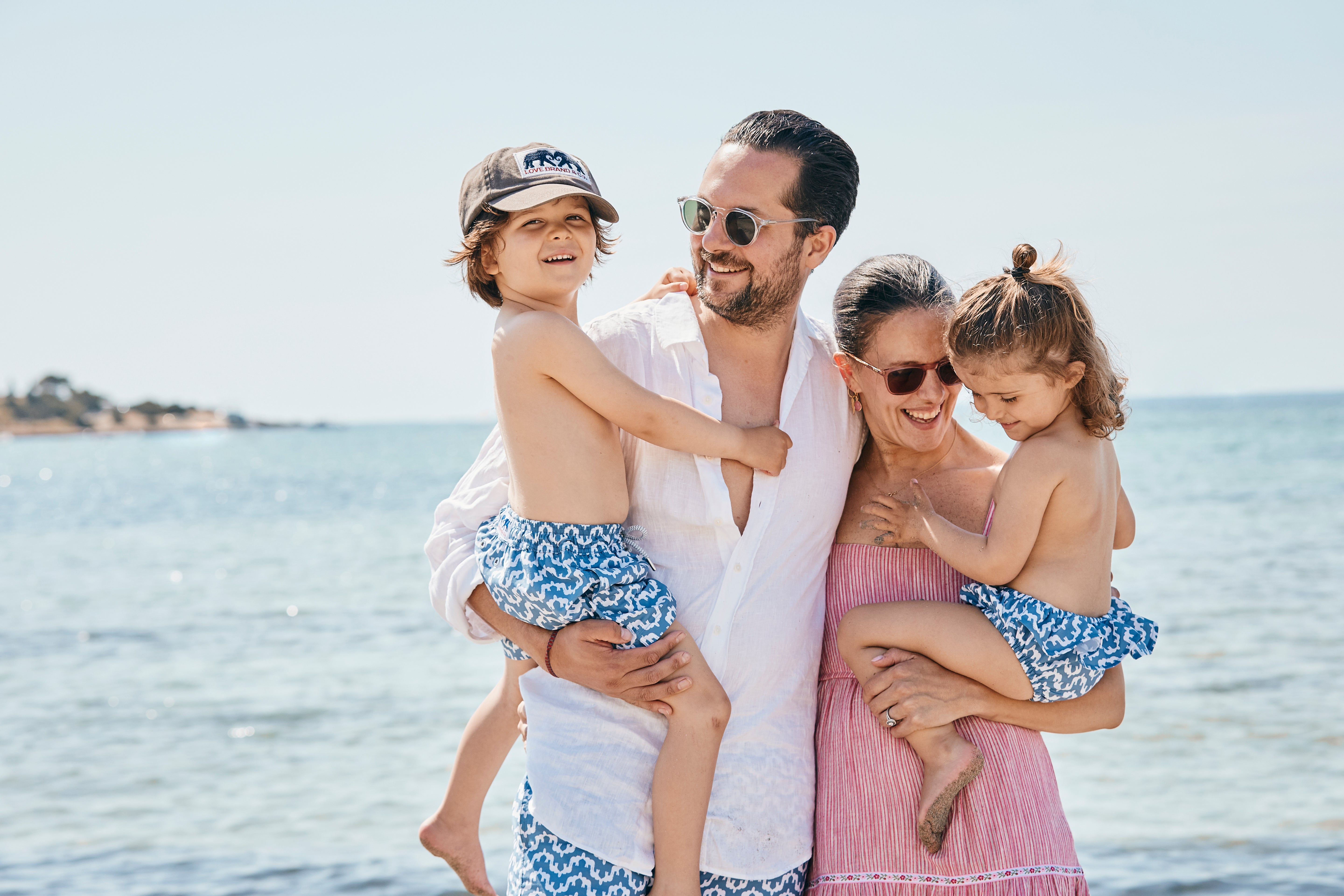 Family of four standing on a beach with ocean in the background