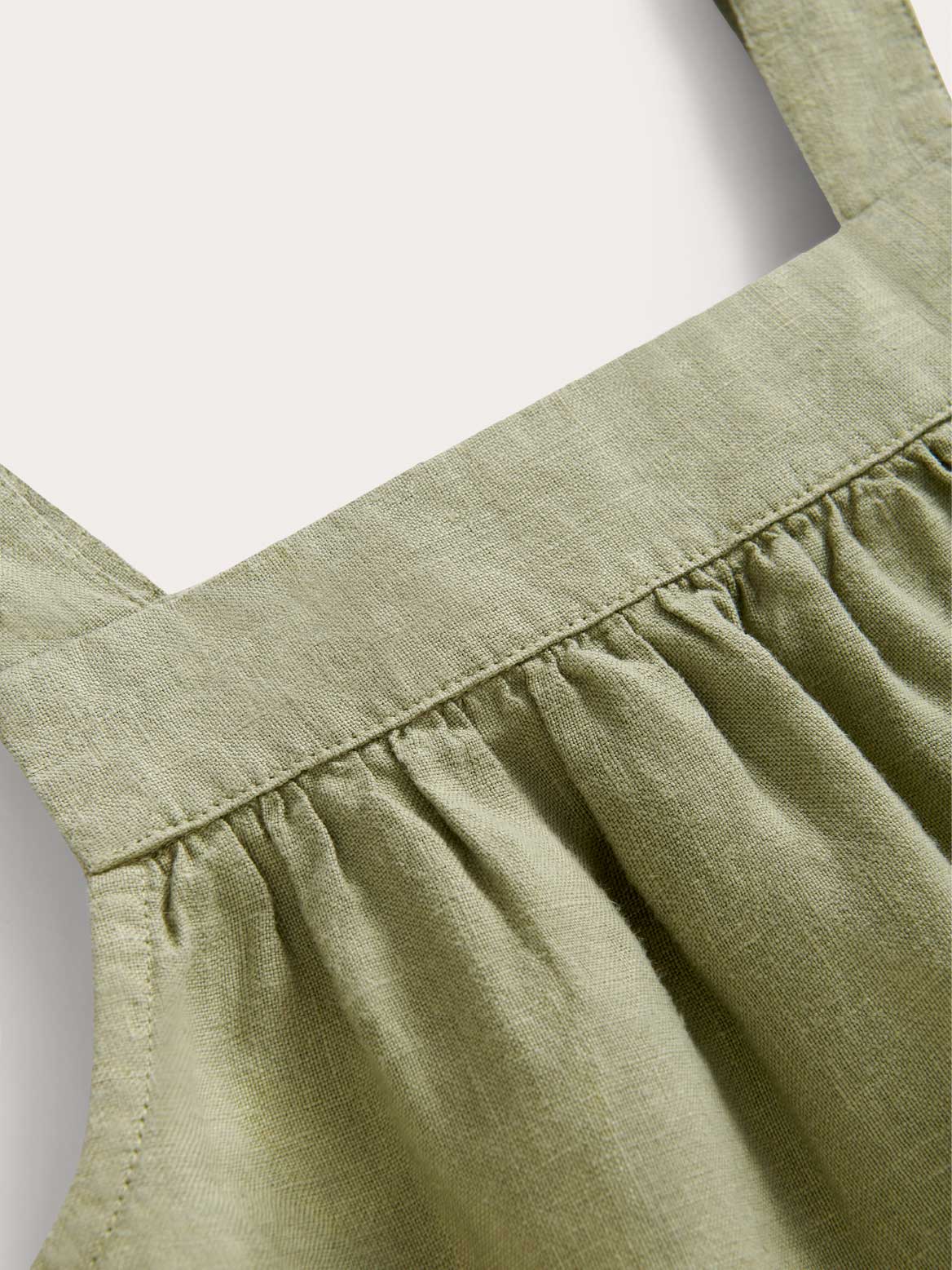 Close-up view of kids green beach dress linen fabric.