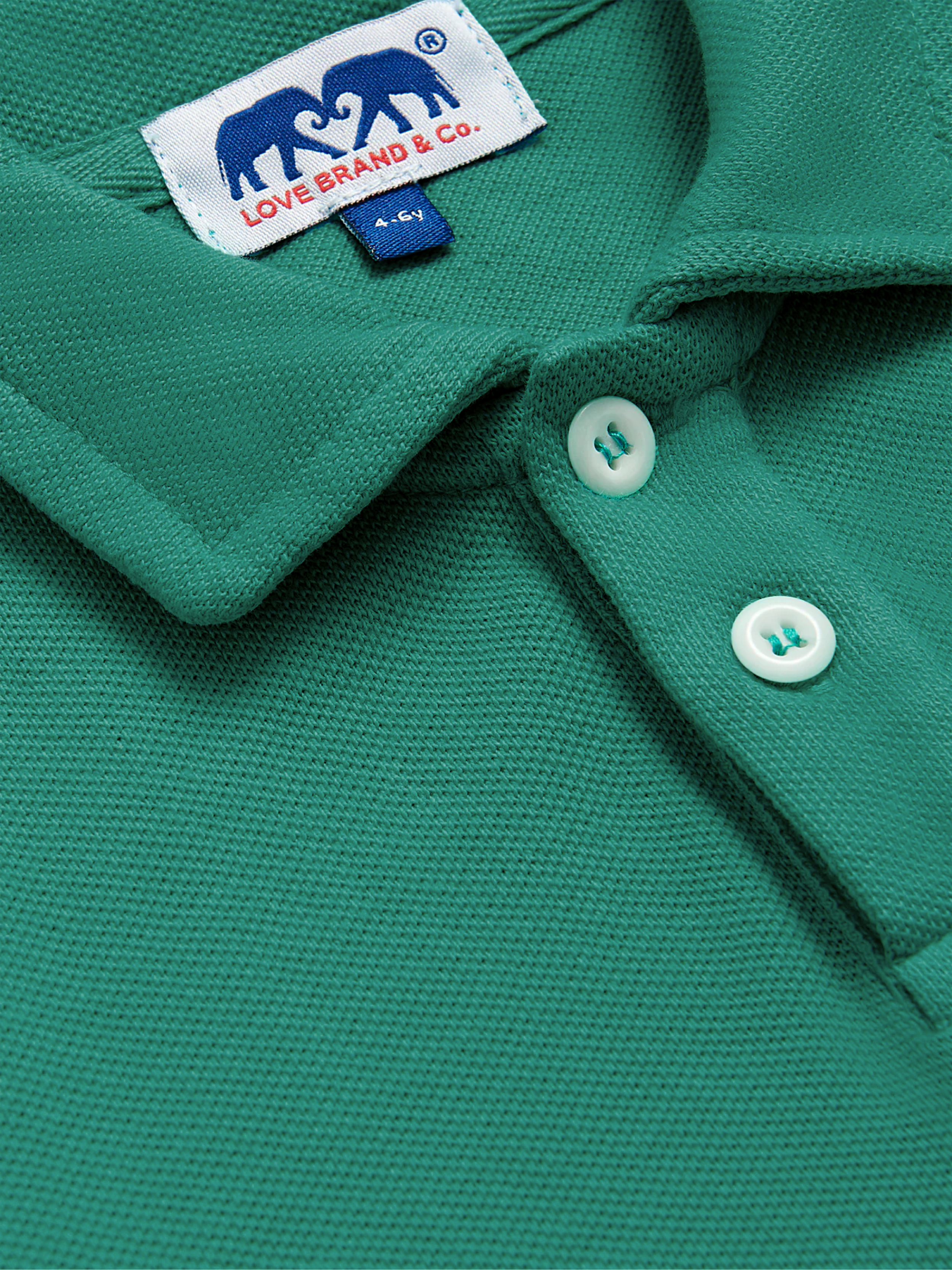 Close-up of a kids green polo shirt with a brand label on the collar.