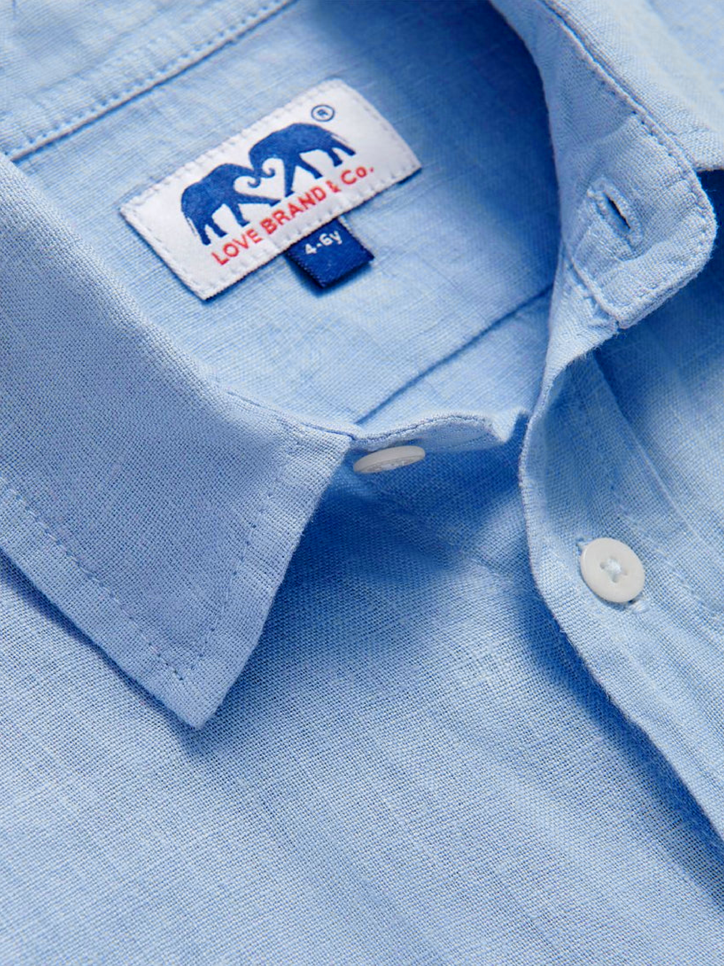Close-up of a light blue shirt for kids with a love brand brand label inside the collar.