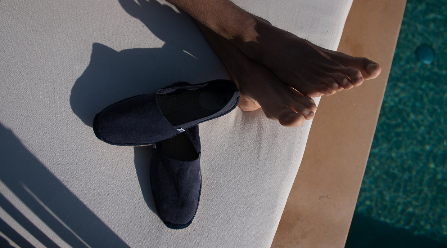 Navy bleu espadrille shoes on a white surface with a blurred background