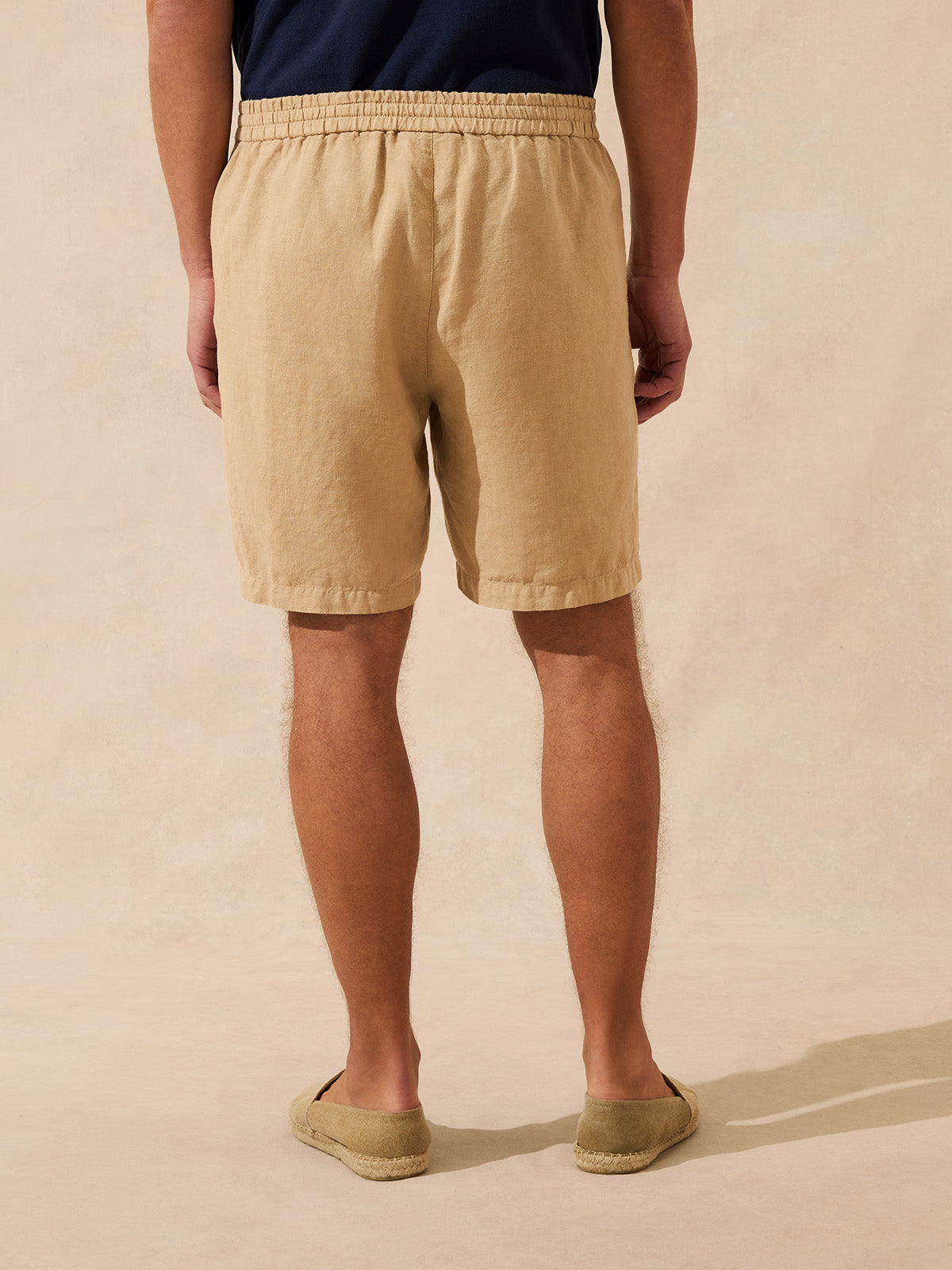 Back view of a man wearing beige linen shorts