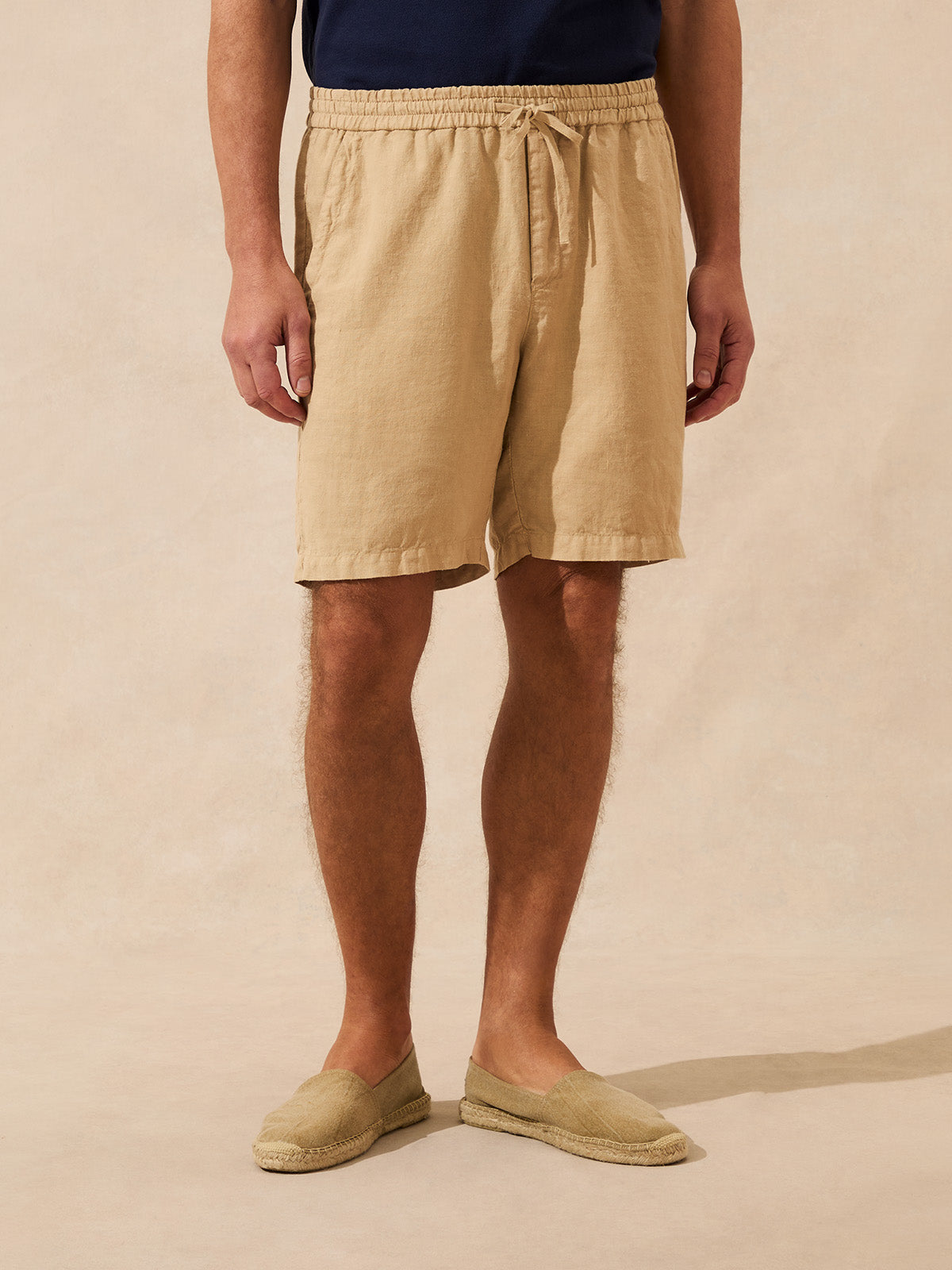 Man wearing beige shorts on a beige background