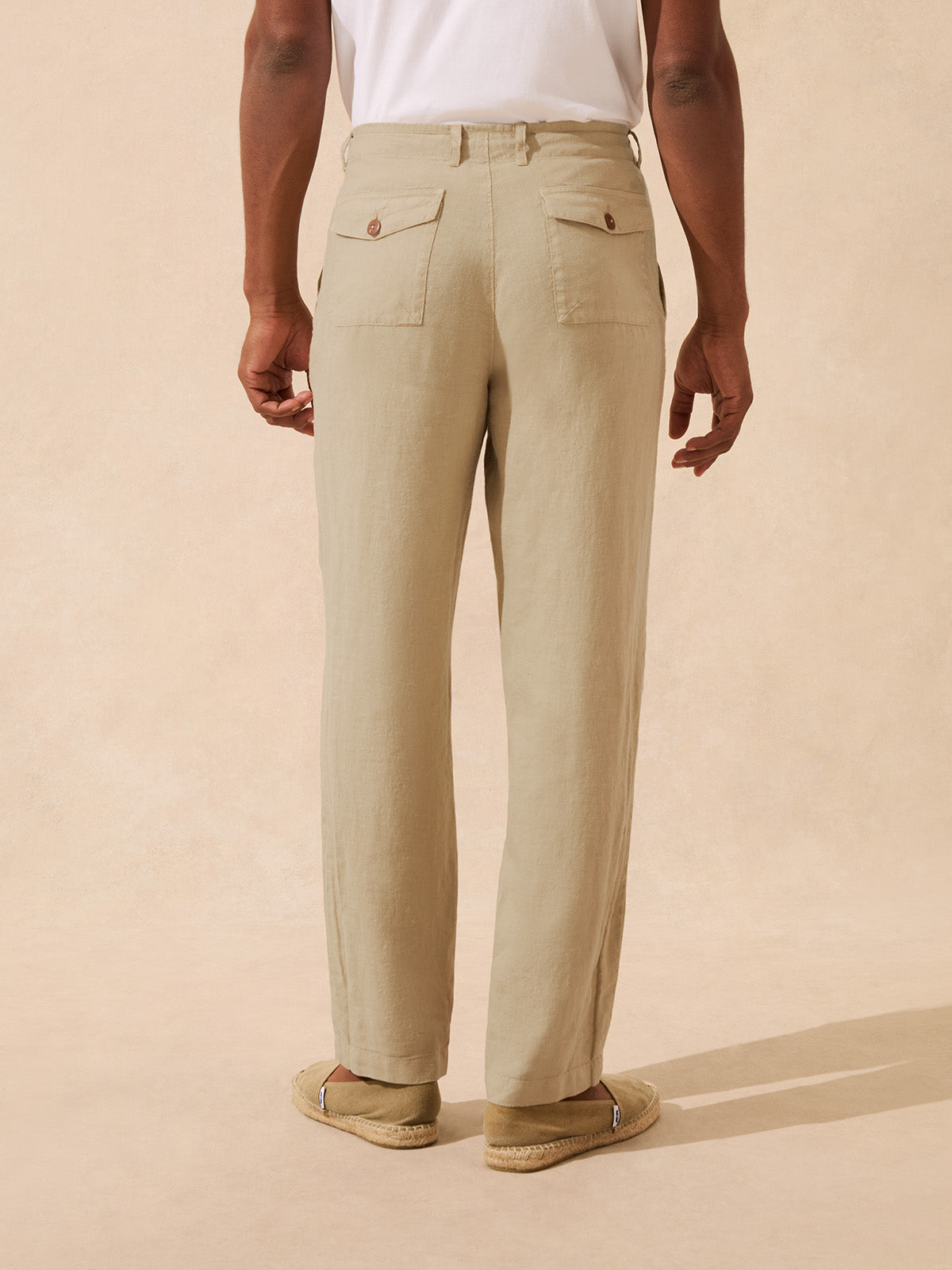 Back view of man wearing beige linen trousers with two back pockets
