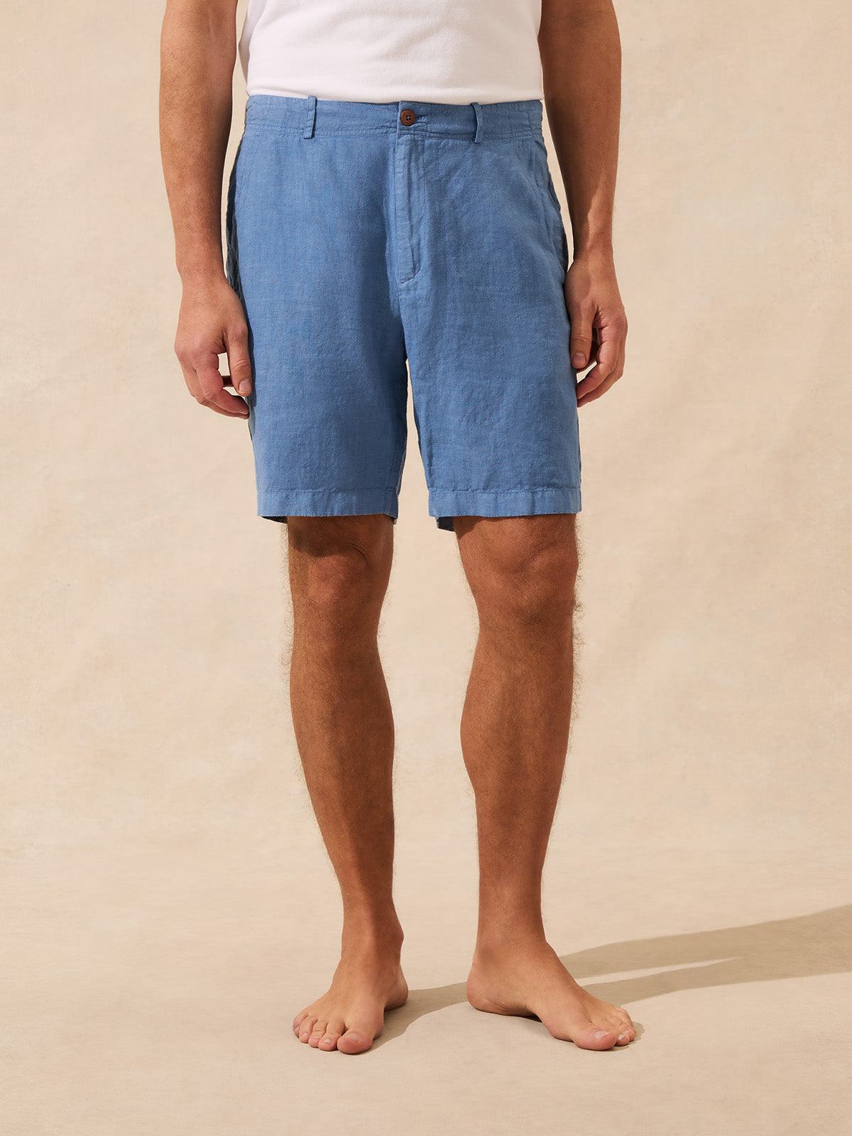 Person wearing blue shorts on a beige background