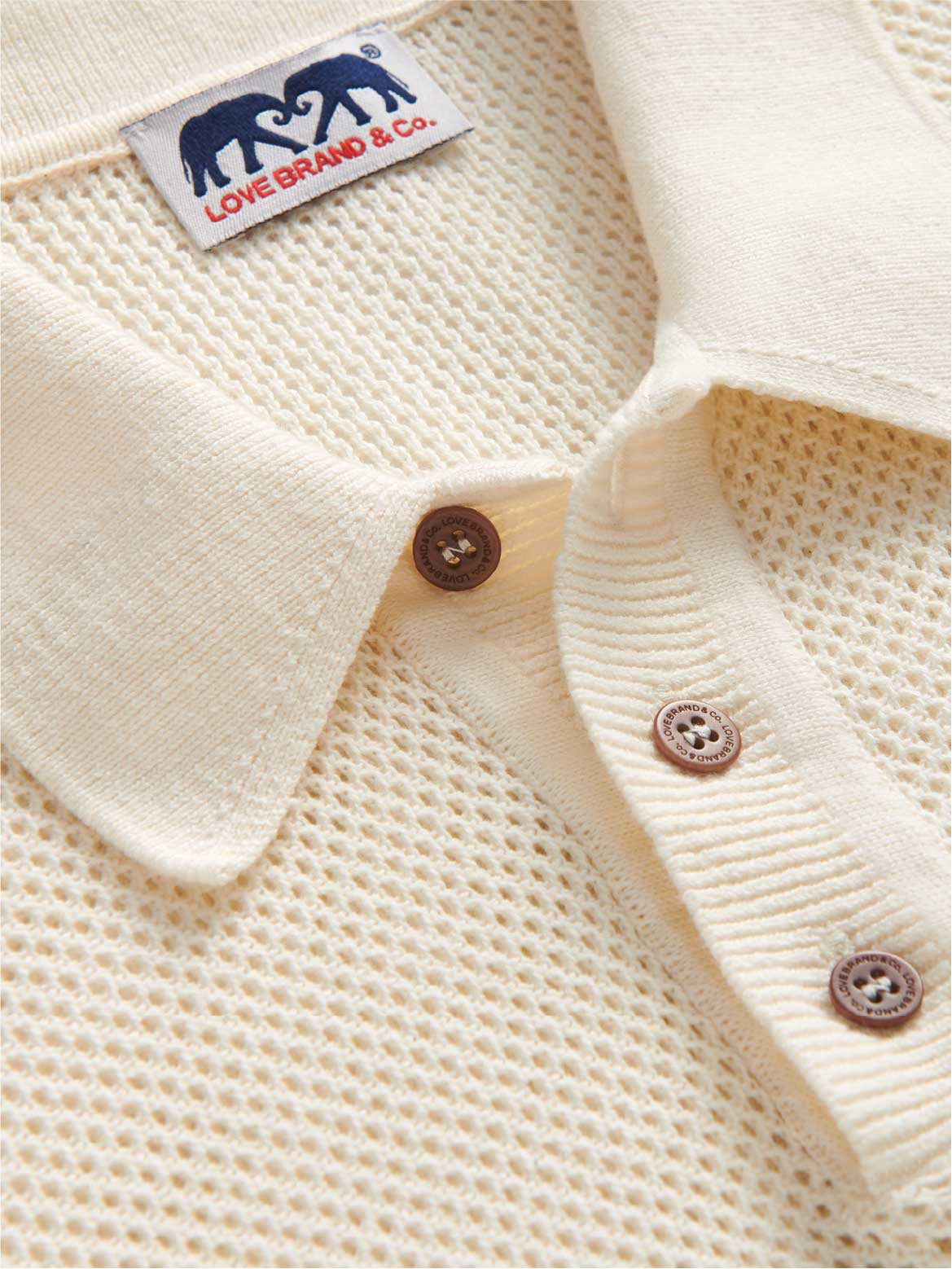 Close-up collar view of mens cream knitted polo shirt showing corozo nut buttons and love brand label.