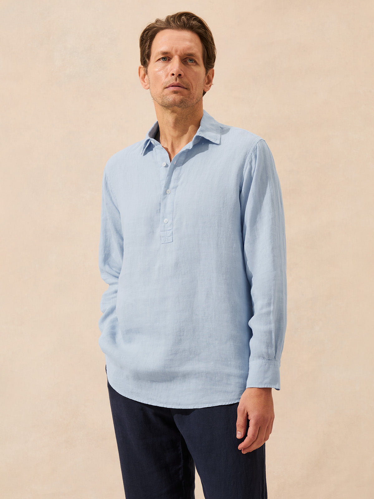 Man wearing a light blue long-sleeve shirt against a beige background