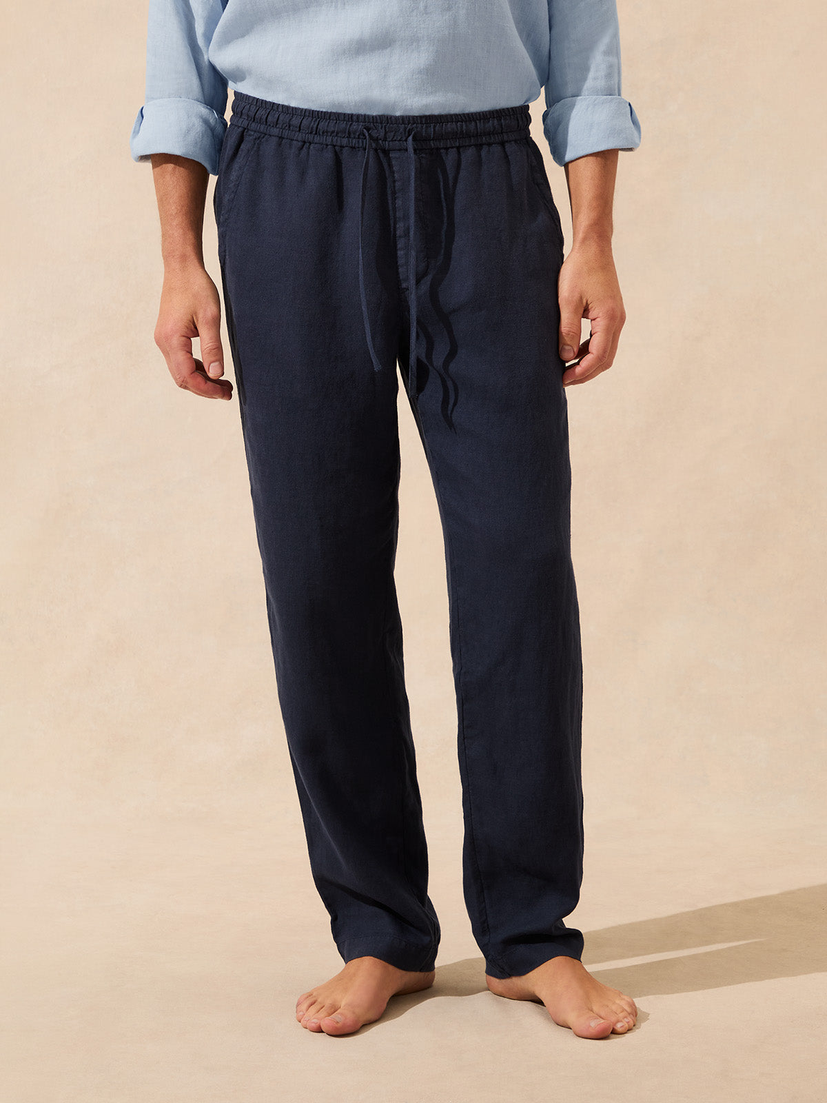 Man wearing navy blue pants on a beige background
