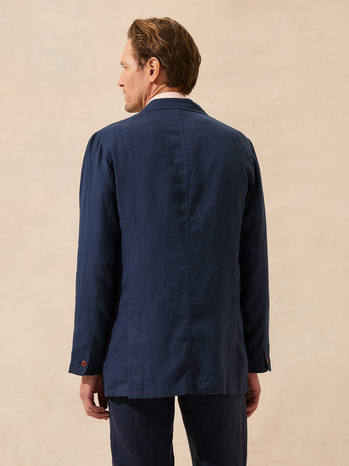 Back view of a man wearing a navy blue linen jacket