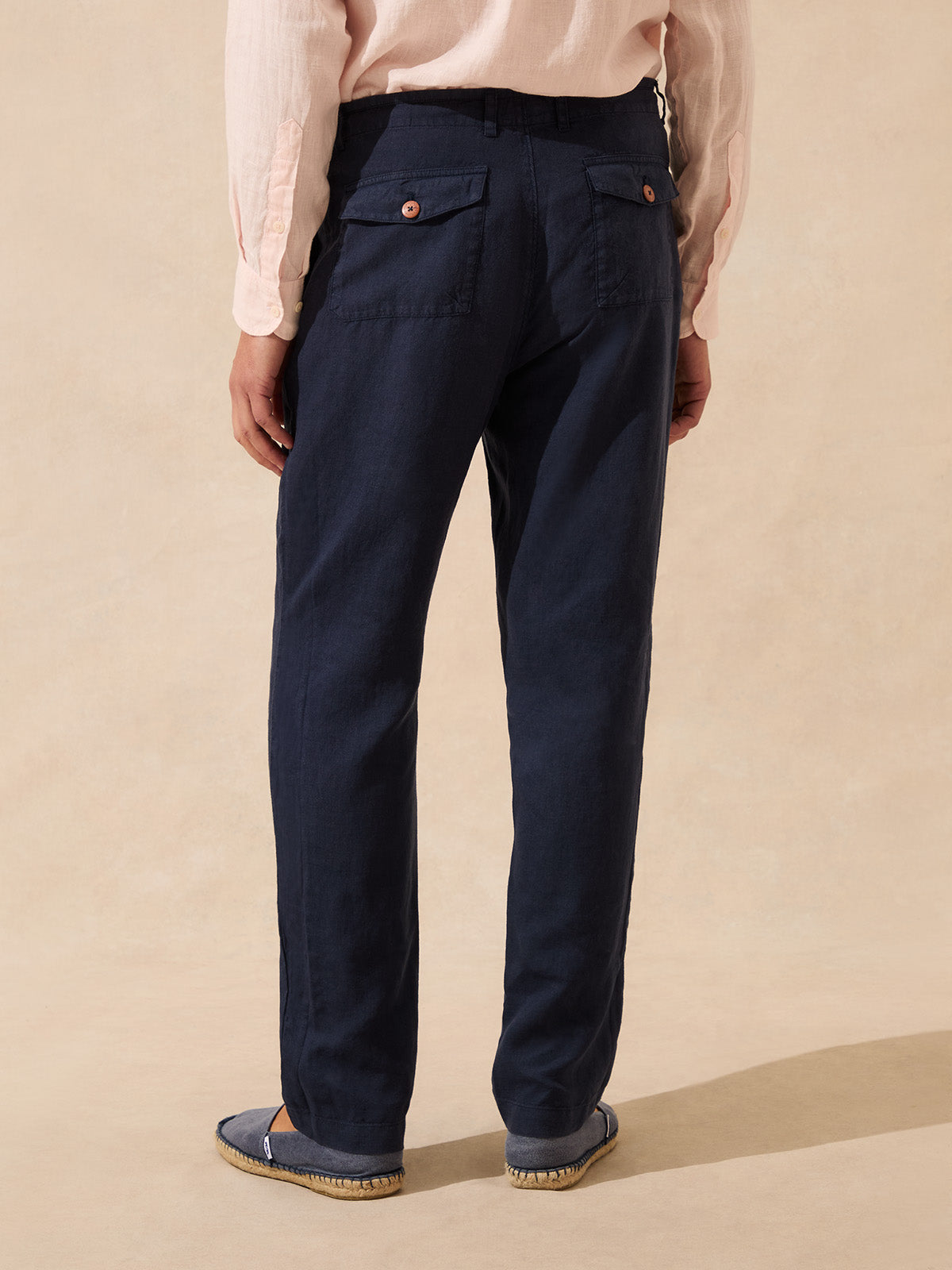 Back view of a man wearing navy linen trousers with two back pockets