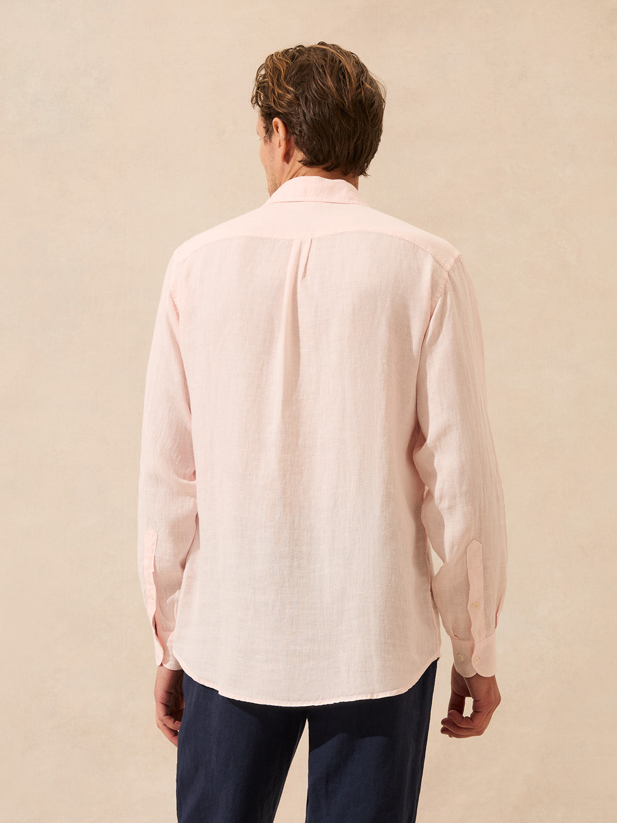 Back view of man wearing a pastel pink linen shirt