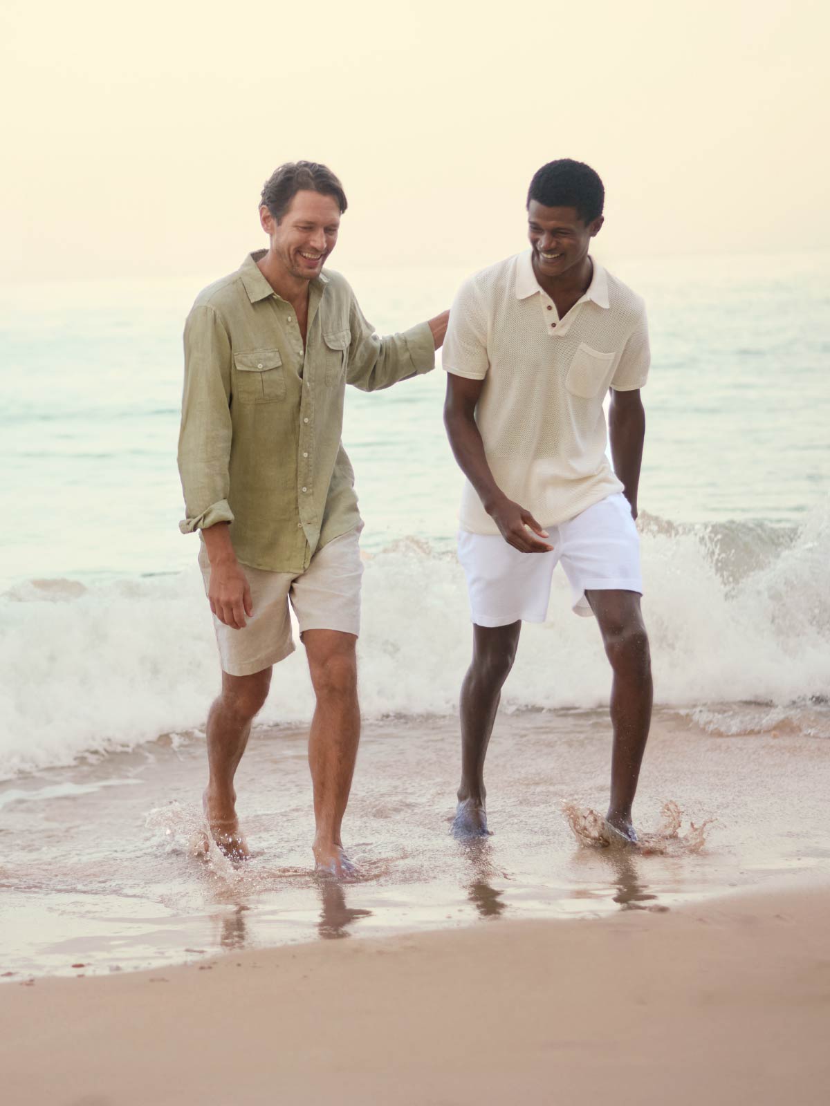 Two men walking on a beach with ocean waves in the background