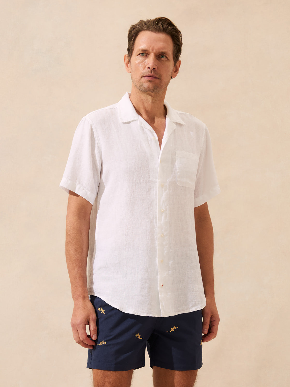 Man wearing a white short-sleeve linen shirt with a beige background