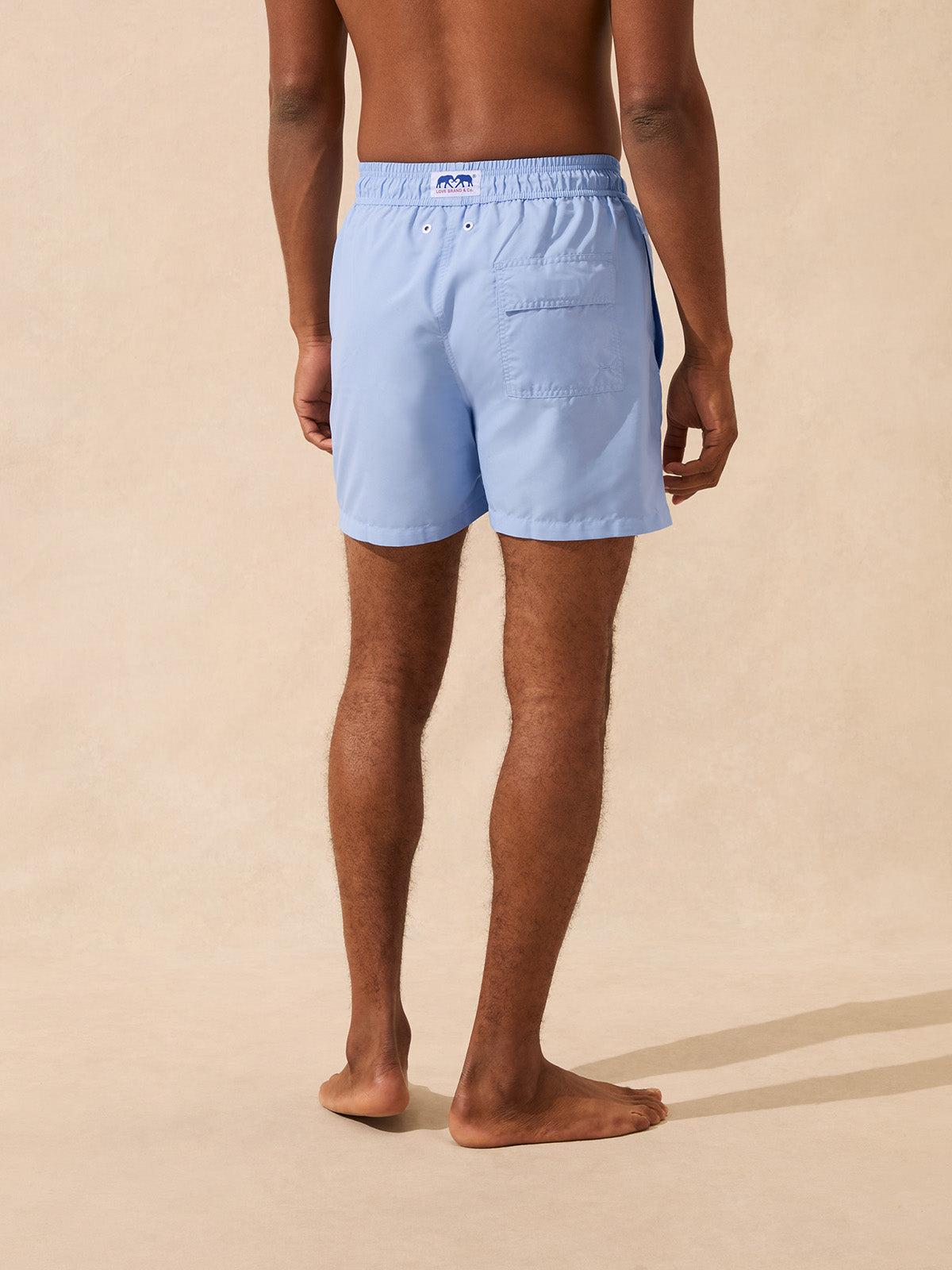 Back view of a man wearing light blue swim shorts showing back pocket detail