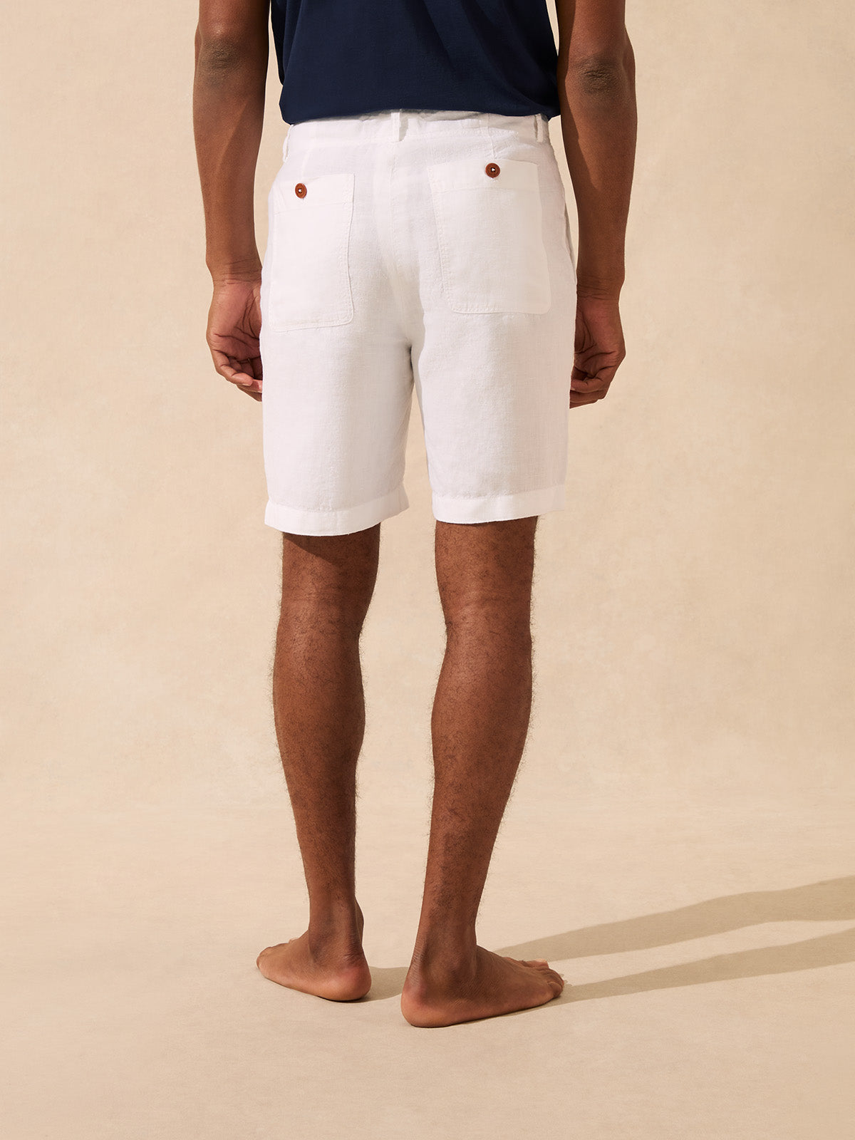 Back view of a man wearing a pair of white shorts with 2 back pockets