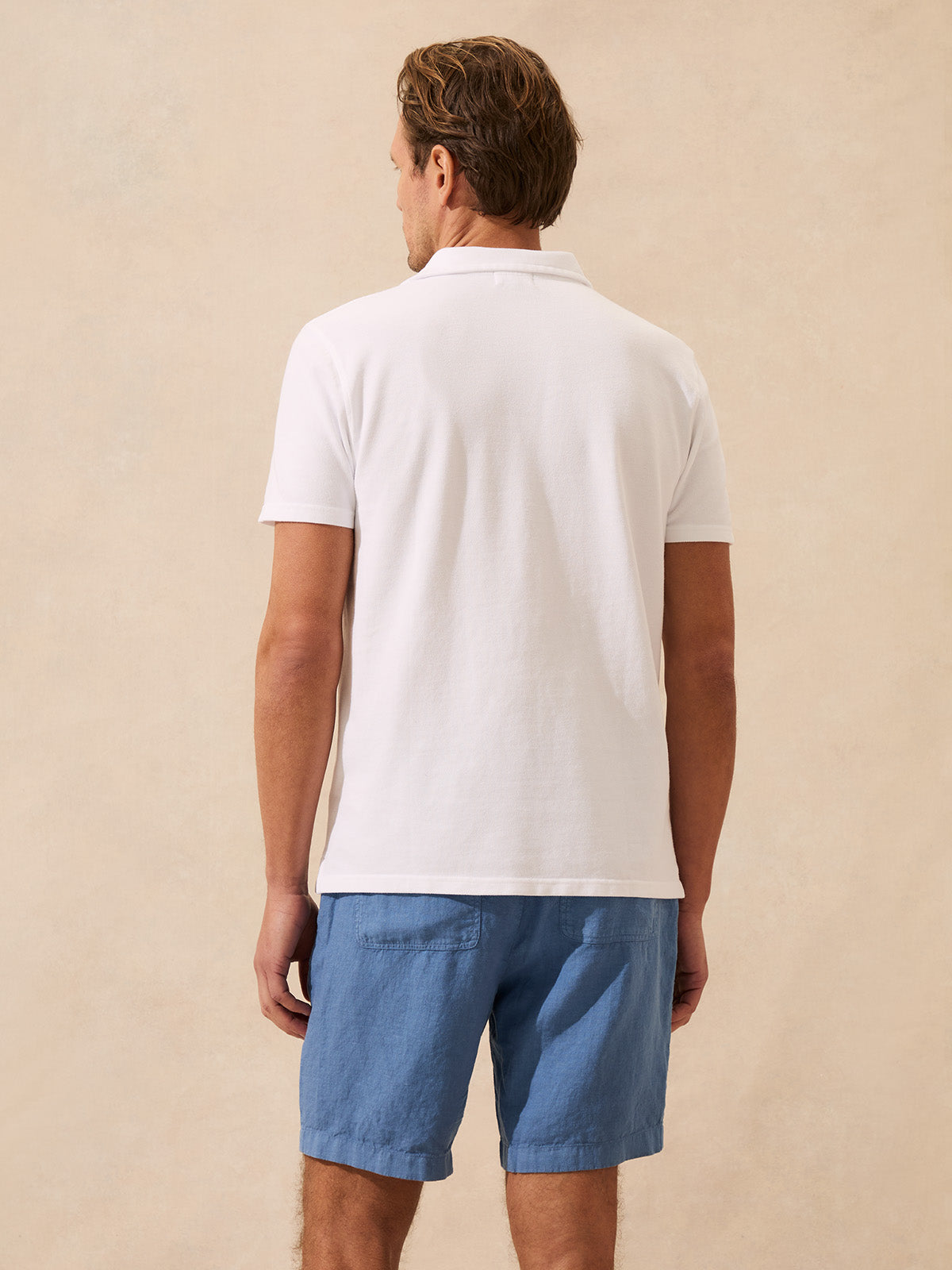 Back view of man wearing a white polo shirt