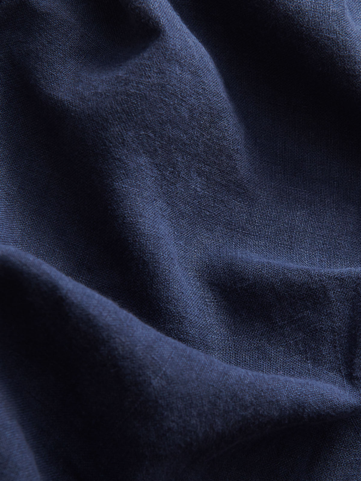 close-up view of navy blue linen fabric of love brand mens navy linen pants.