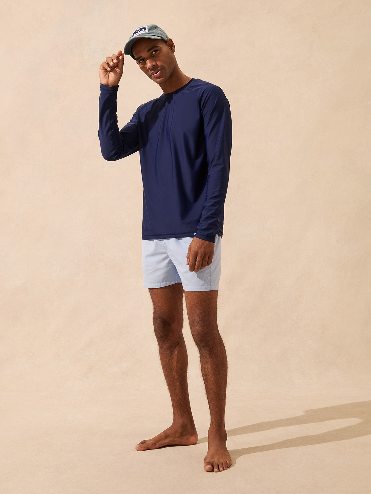 Man wears a long sleeve navy rash vest and swim shorts